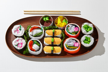 Set of paper sushi on a wooden plate over white background. Top view with copy space. Pure and fresh concept and composition.