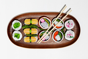 Set of paper sushi on a wooden plate over white background. Top view with copy space. Pure and fresh concept and composition.