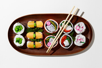 Set of paper sushi on a wooden plate over white background. Top view with copy space. Pure and fresh concept and composition.