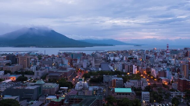 Kagoshima, Japan. View of mountain Sakurajima an active volcano. Aerial view of Kagoshima city in Japan at sunrise. Time-lapse with volcano eruption in the morning