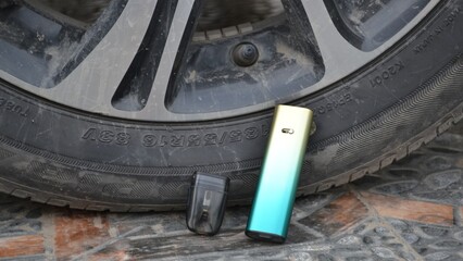 Vape devices next to dirty car tire on stone floor