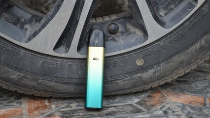 E-cigarette leaning against dirty car tire on stone floor