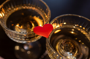 wo champagne glasses with a red heart between them on a dark romantic background