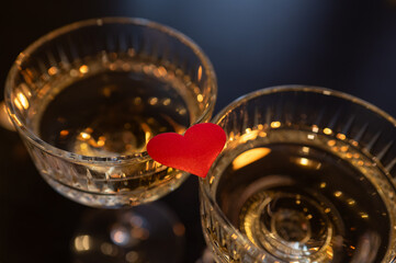 wo champagne glasses with a red heart between them on a dark romantic background