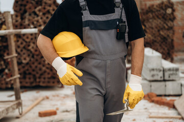 Safety first, holding protective helmet. Close up view of builder that is on the construction site