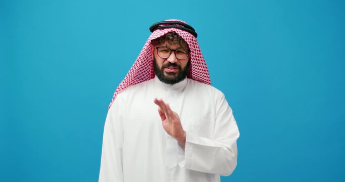 Serious muslim man wearing stylish keffiyeh feeling unpleasant smell showing stop sign