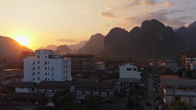 Hot air balloon flying over Vang Vieng mountains in Laos at sunset. Majestic Southeast Asian landscape with limestone karsts