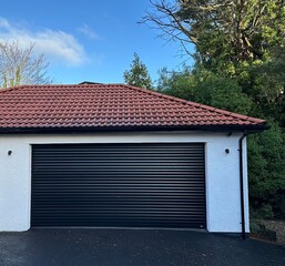 Modern garage outbuilding with red terracotta tiled roof and blue sky
