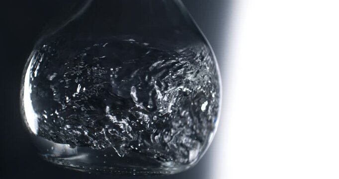 Slow Motion Clear Liquid Swirling Inside Glass Container On Dark Background. Pure Water Or Alcohol Motion, Abstract Beverage Texture And Cinematic Flow
