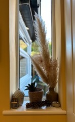 Window decorations on a sill with plants and misc accents
