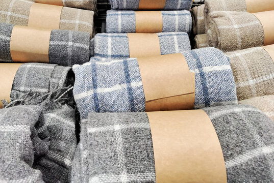 Mobile photo rolled plaid blankets. Cozy home textiles, retail display, warm fabric, winter comfort, shopping concept, interior decor, soft household goods.