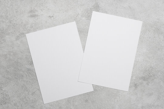 Two blank white cards on grey concrete background, ideal for greeting cards, wedding invitation or flyer designs presentation or minimalist stationery
