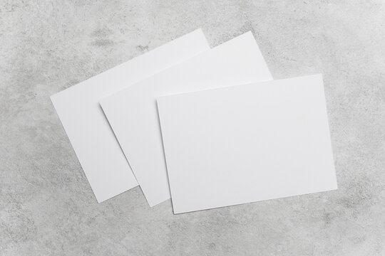 Three blank cards on grey concrete background, ideal for greeting, invitation or flyer designs presentation, wedding cards, or minimalist stationery