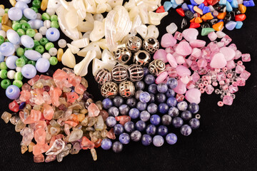 A variety of beads made of natural stone, glass, mother-of-pearl, ceramics and metal on a black background	