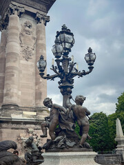 Putti figures and a luxurious street lamp adorn the Alexandre III Bridge. View of the the Pont Alexandre III bridge over the Seine River in spring Paris, France.
