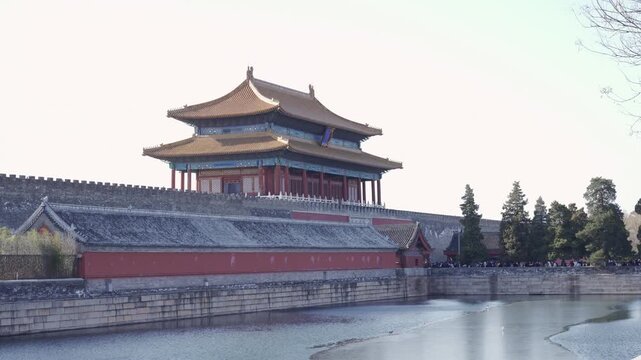 view to ancient wall of forbidden city with chinese archiecture wooden building on the wall in winter sunny daytime and frozen canel