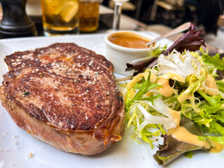 Juicy ribeye steak with a delicious crust, lettuce and meat sauce in one of the French cuisine restaurants, Paris, France.