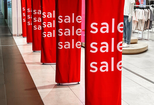 Bright red sale banners attract shoppers in a busy mall