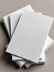 Blank white textured business cards in stack on neutral surface