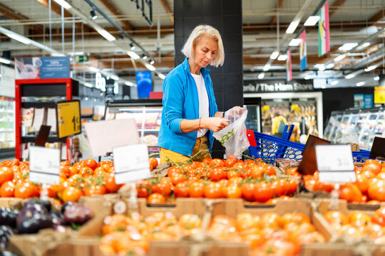 Elderly woman choosing fresh food in supermarket