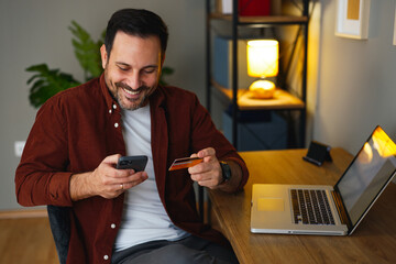 Smiling man using mobile banking app at home