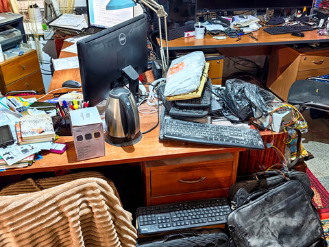Kirov, Russia - November 07, 2025: Messy home workspace with computer, cables, documents and household items, chaotic interior showing cluttered desk, disorder and everyday life