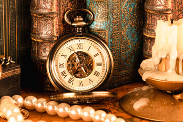 Antique mechanical clock against a background of vintage books. Retro style.