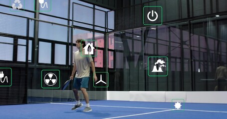 Holding paddle, man in blue shorts moving on blue court at gym, AR icons, copy space