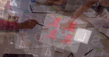 Pointing two coworkers in shirts studying reports with red data at office, with digital overlay © vectorfusionart