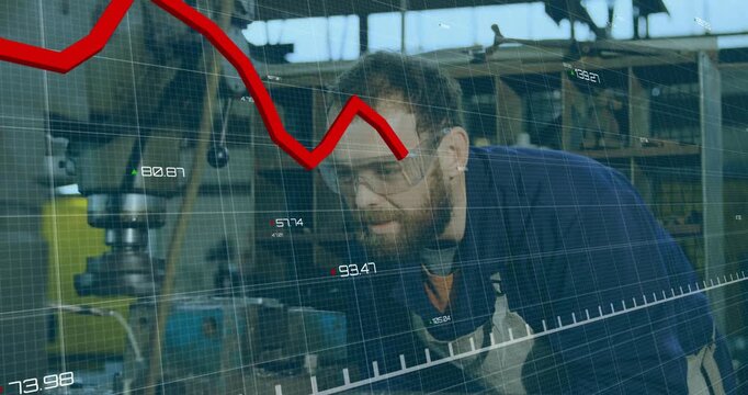 Machinist raising goggles, inspecting drill in shop and checking output while HUD red graph moving
