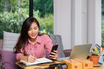 Cheerful business woman receiving good news or payment confirmation via smartphone. Successful e-commerce concept with laptop and equipment.