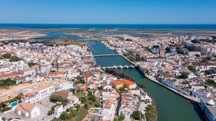Fototapeta premium A drone view captures Tavira in Algarve with rivers, Roman bridges, and various structures. The coastline and landscapes are visible in the background