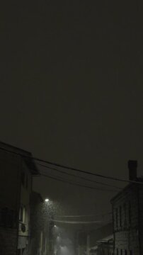 Heavy snow falls on a silent residential street in &Aacute;vila at night, covering pavements, parked cars and trees, while soft street lighting adds a peaceful, wintry atmosphere to the urban landscape.