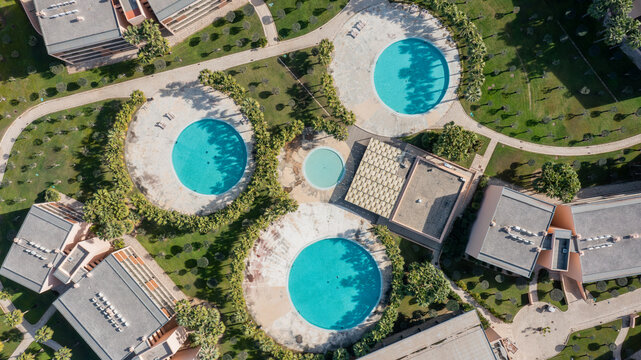 Aerial view shows three circular pools surrounded by green areas and buildings in Salgados, Albufeira, Algarve during daytime
