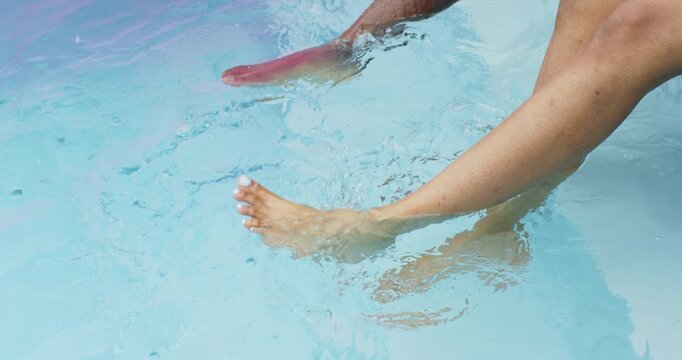 Light feet are flexing poolside, cooling as darker foot is entering, rippling near pink float