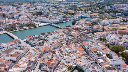 Obraz premium The aerial view captures Tavira with its white buildings, orange rooftops, and winding streets along the Gilao river in Algarve, Portugal on a sunny day