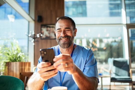Smiling healthcare worker using smartphone during coffee break in cafe