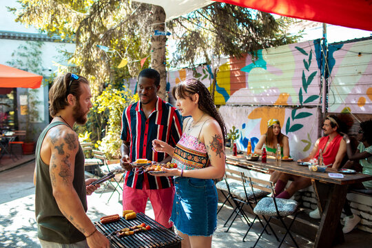 Friends grilling and eating at urban backyard party