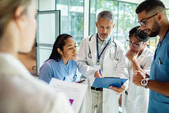 Doctors and nurses discuss patient case in hospital corridor