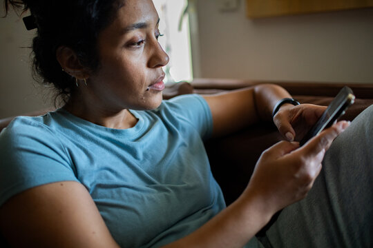 Woman at home using smartphone on couch