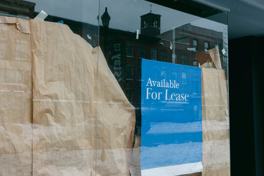 Storefront is empty and closed with a leasing sign in a city street during winter time