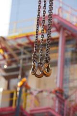 Close-up of industrial lifting chains and hooks used for equipment handling at an energy facility, ideal for: asset management, maintenance operations, industrial safety, energy infrastructure.