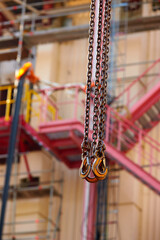 Close-up of industrial lifting chains and hooks used for equipment handling at an energy facility, ideal for: asset management, maintenance operations, industrial safety, energy infrastructure.