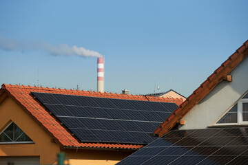 Solar panels installed on residential rooftops with power plant in background, illustrating smart city energy transition. Ideal for: renewable energy, decarbonization, urban sustainability.