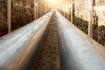 Industrial site showcasing the installation of pre-insulated steel pipelines in a trench. Ideal for: district heating project reports, energy efficiency articles, and utility maintenance news.
