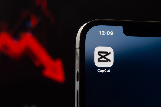 Smartphone screen displaying CapCut logo against a red falling stock graph representing video tech market volatility. Sonora, Mexico - January 28, 2026