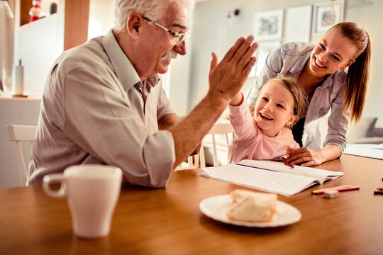 Grandfather and girl high-fiving during homework at home