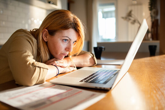 Concerned woman reviewing bills on laptop at home