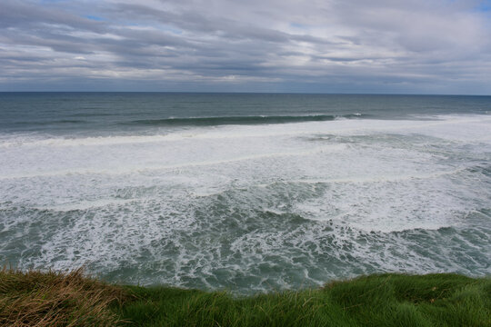 Paisaje de mar, cielo y c&eacute;sped. Espuma de mar formada por la resaca de la marea en la bajamar.