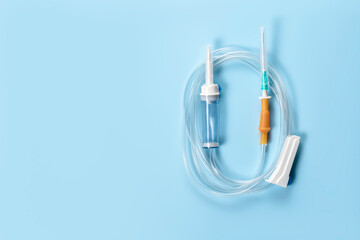 Dropper with sharp needle and tube regulator on blue background.